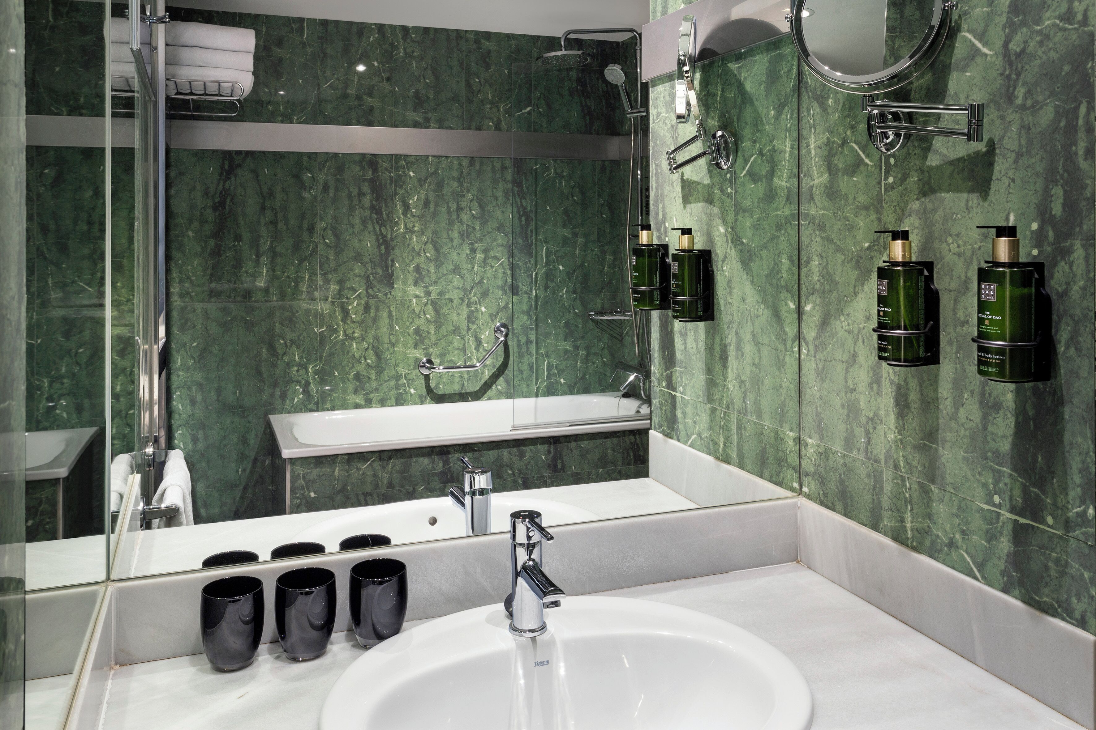 A modern bathroom with a white sink, a large mirror, and a shower area.