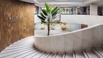 A modern interior with a wooden wall, a central plant, and a curved staircase.