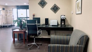 Un bureau d’hôtel équipé d’un bureau, d’un ordinateur, d’une imprimante, d’une machine à café et d’un fauteuil à motifs.