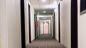 Un long couloir étroit, avec un tapis à motifs, un sol carrelé et des portes de part et d’autre.