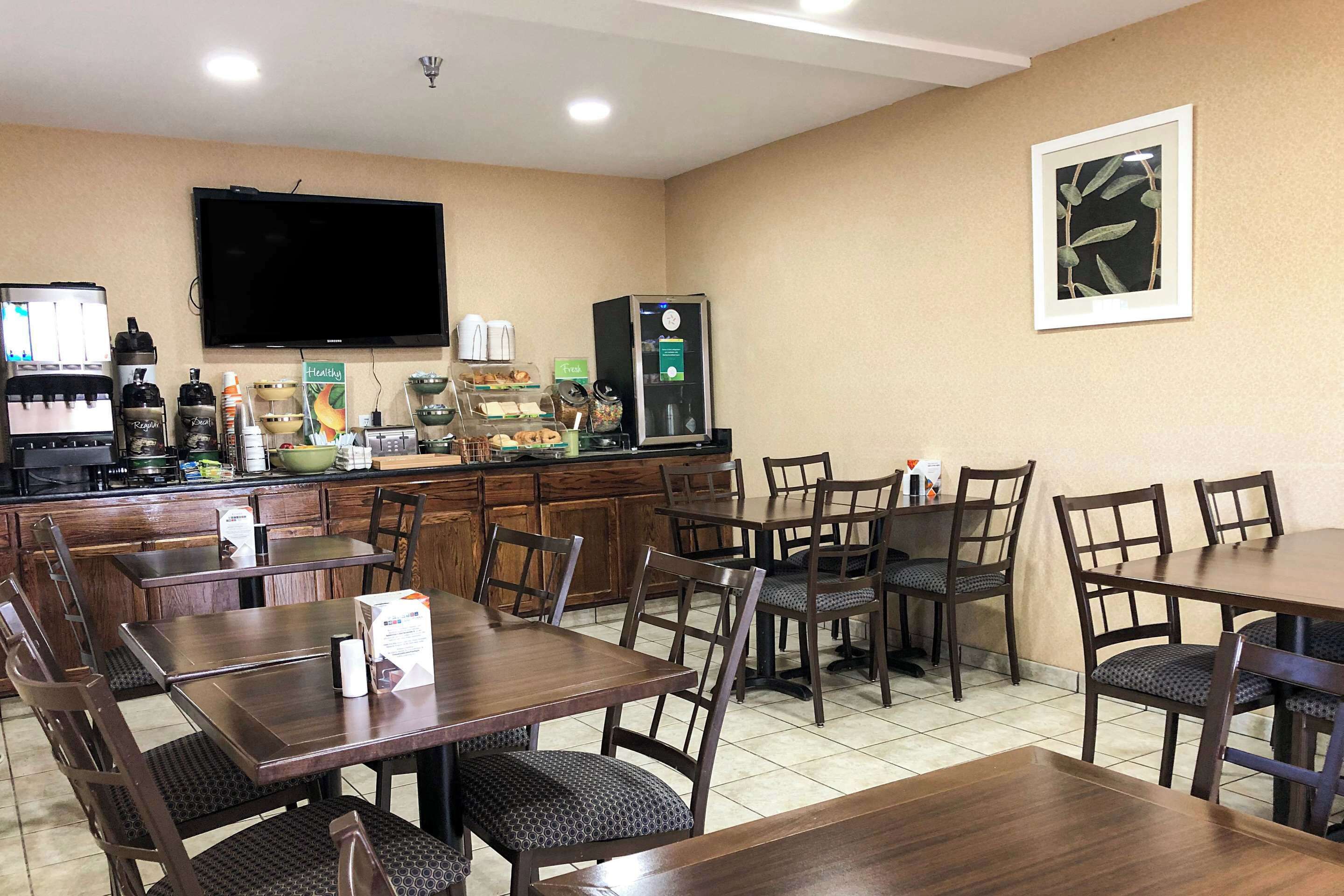 A dining area with wooden tables and chairs, a coffee machine, and a television mounted on the wall.