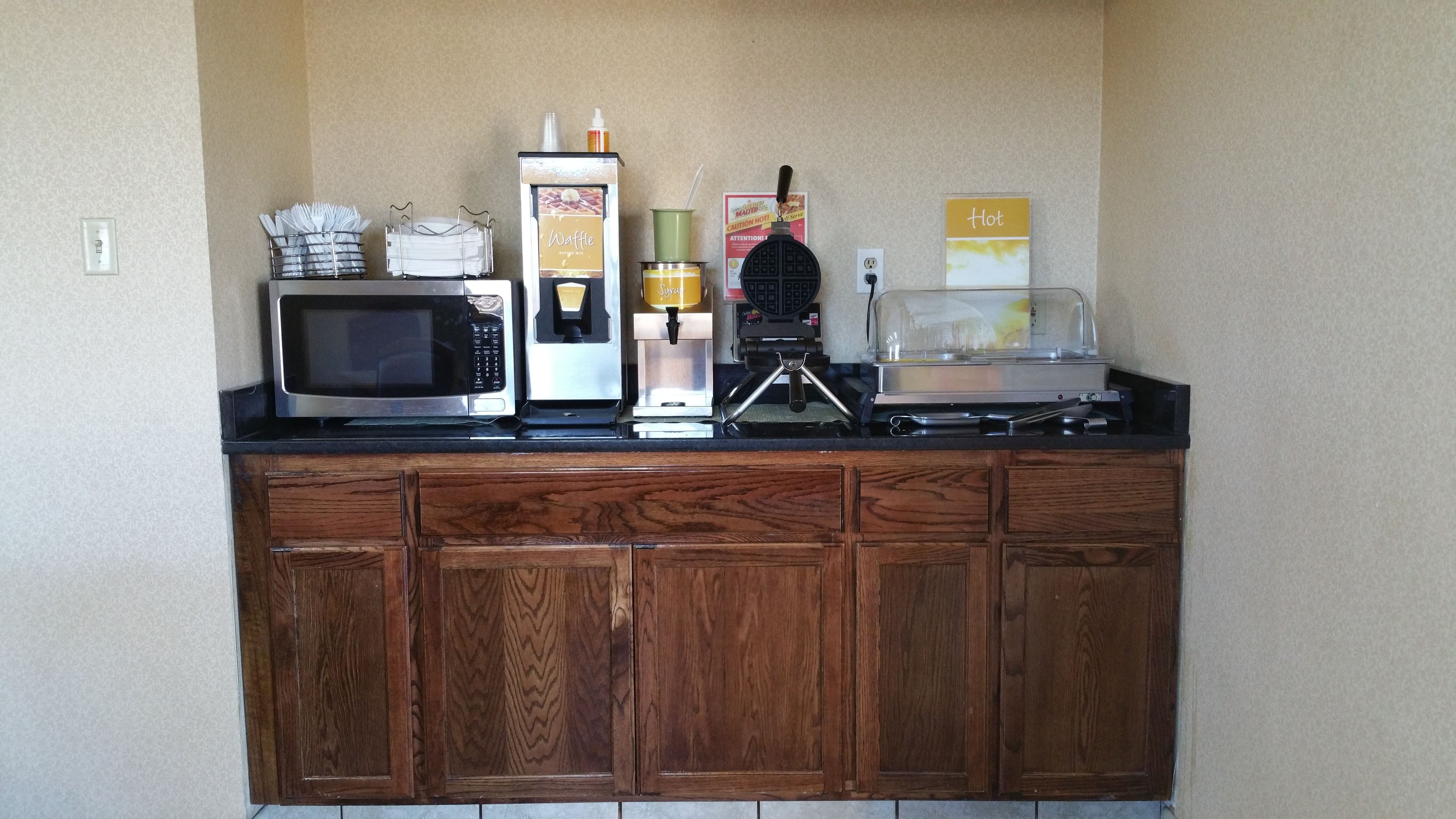 Una kitchenette equipada con microondas, cafetera, plancha para gofres y tostadora.