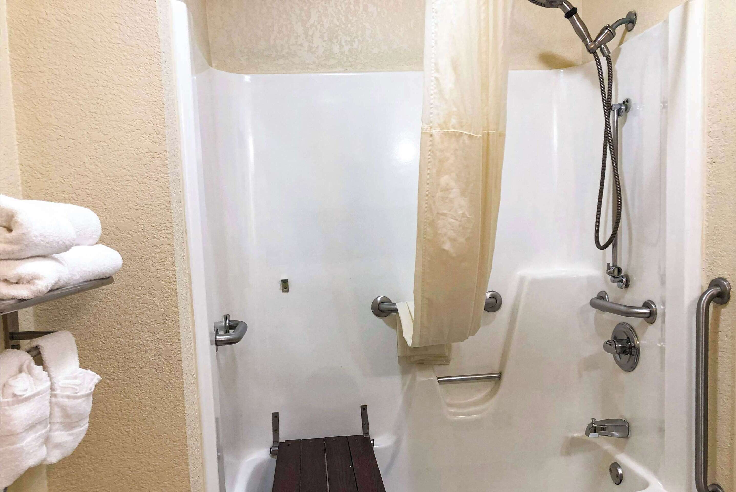 A shower area with a grab bar, a towel rack, and a showerhead.