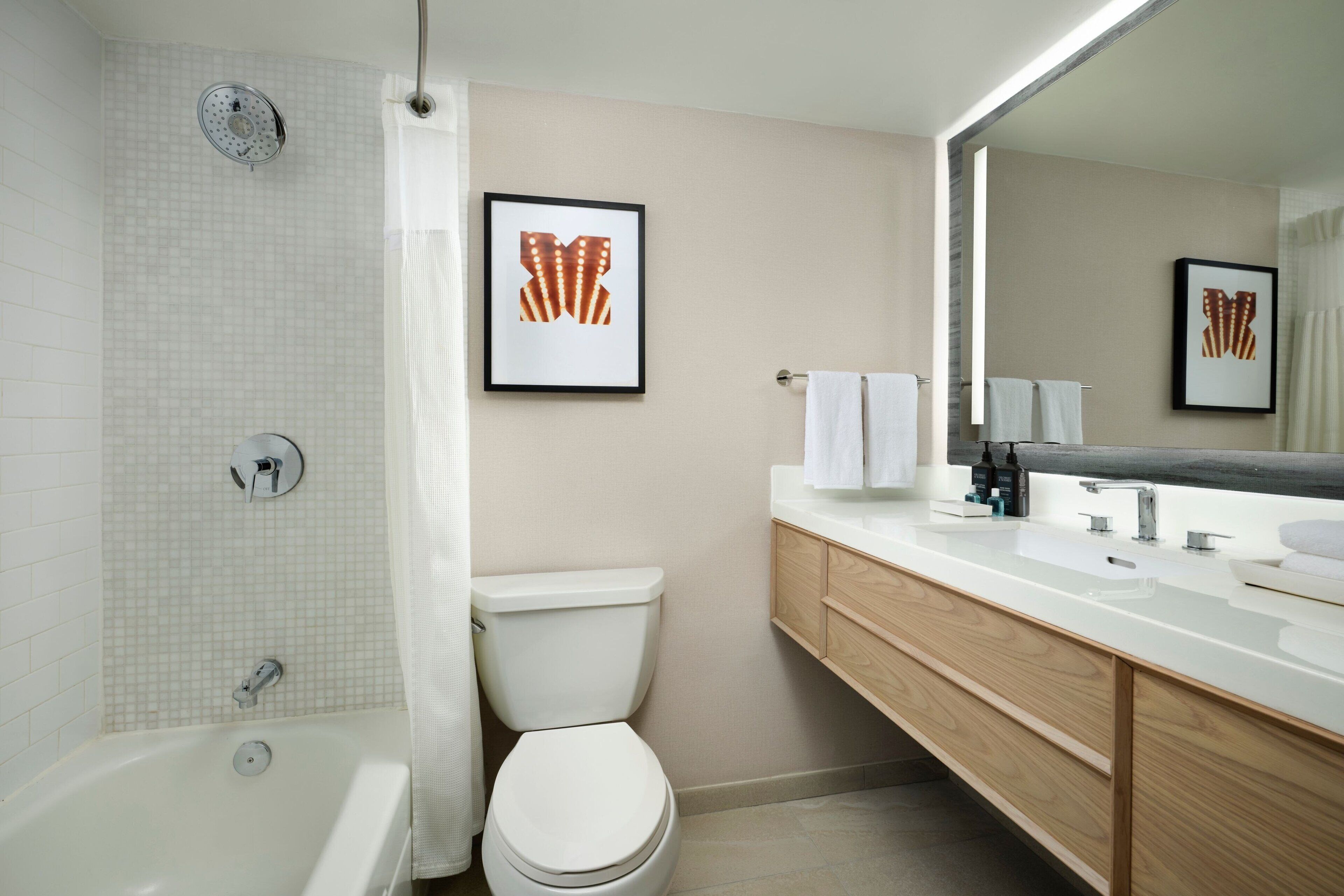A modern bathroom with a bathtub, toilet, and vanity with a large mirror.