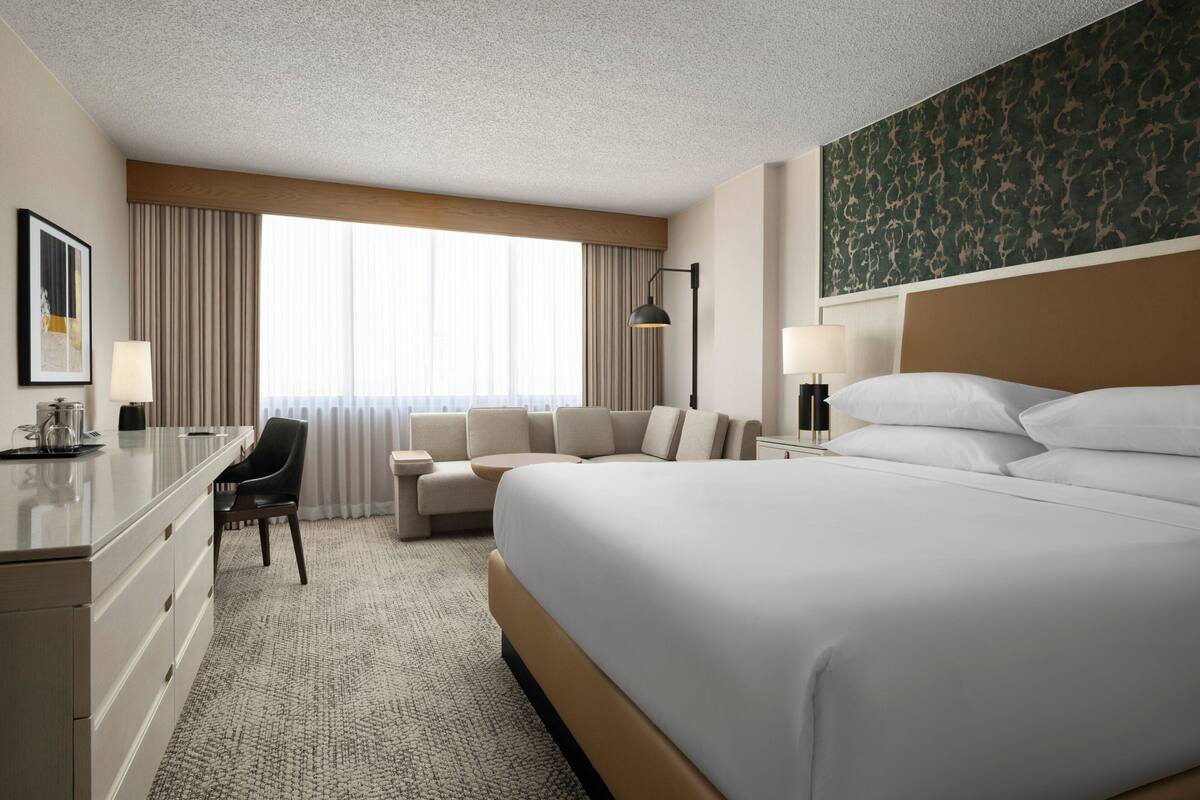 Une chambre d’hôtel avec un grand lit, un bureau, une chaise et un canapé.