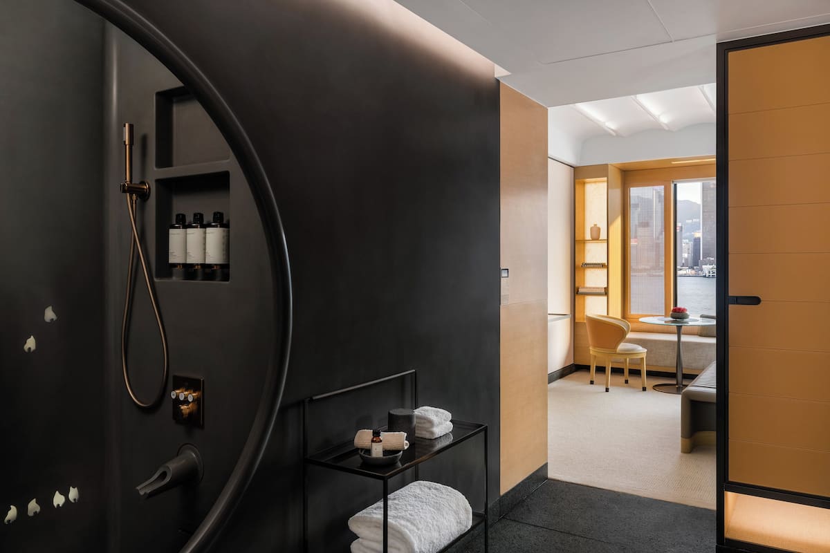 Une salle de bain moderne avec un meuble-lavabo noir, une douche et une petite table sur laquelle sont posées des serviettes et des articles de toilette.