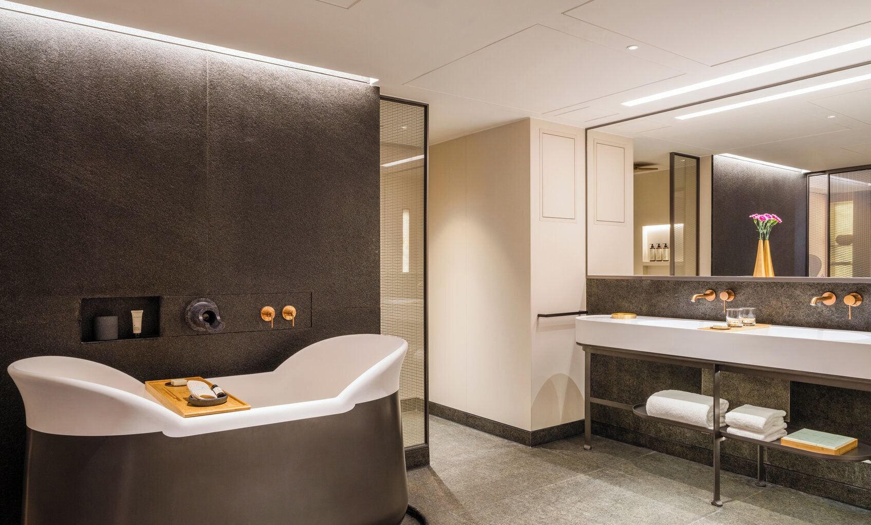 Un baño moderno con una bañera independiente, un tocador con un espejo grande y un perchero para toallas.