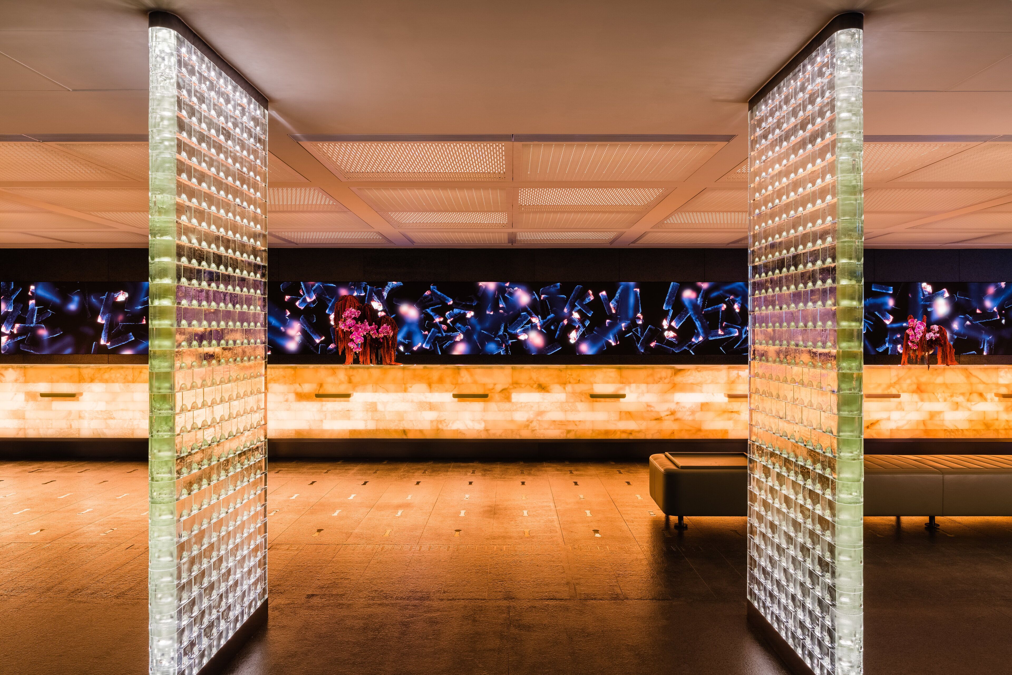 A modern lobby with a glass partition, a reception desk, and a seating area.