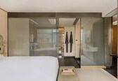 A hotel room with a bed, a bedside table, a TV, and a sliding door leading to a bathroom.