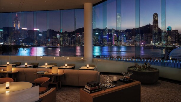 A modern hotel lobby with large windows offering a nighttime cityscape view. - Regent Hong Kong (Kowloon)