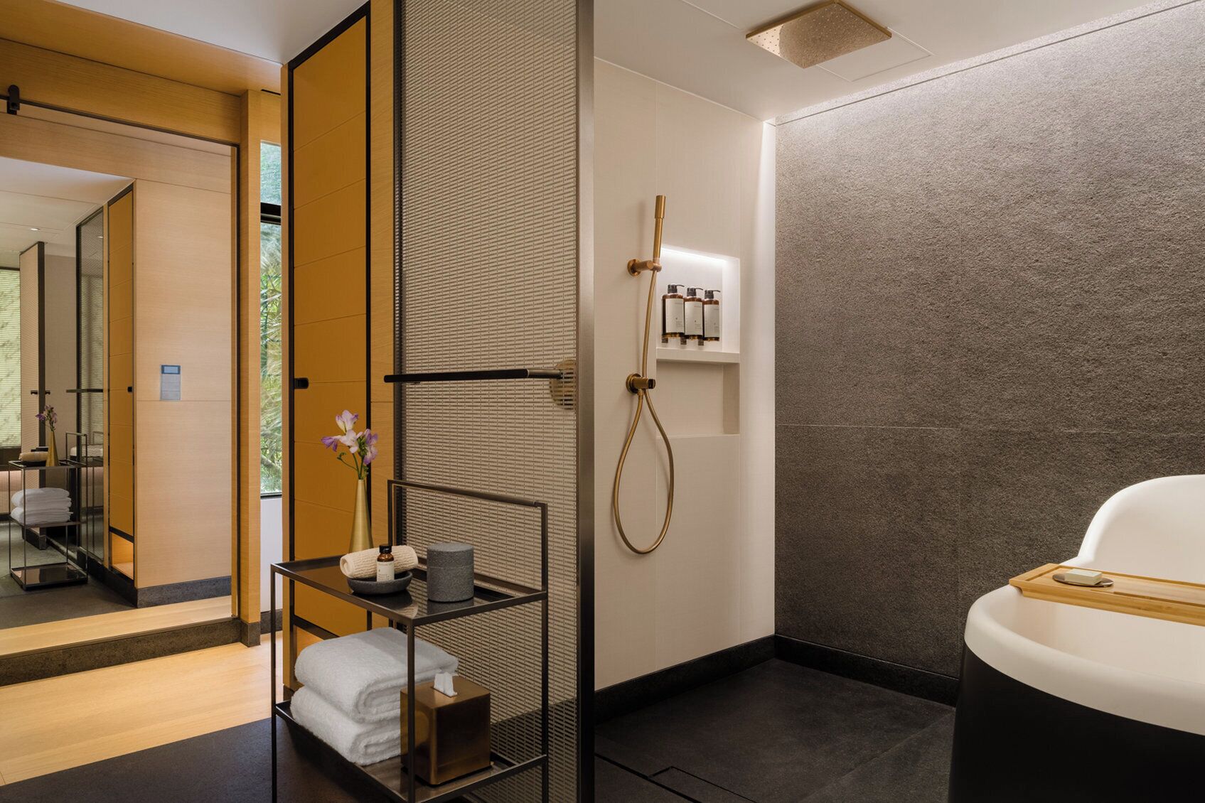 A modern bathroom with a shower, a bathtub, and a toilet. There is a towel rack and a shelf with toiletries.