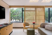 A modern living room with a sofa, a round glass table, a chair, and a TV mounted on the wall.