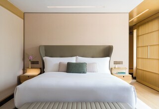 A modern hotel room with a large bed, a nightstand, and a bedside table.
