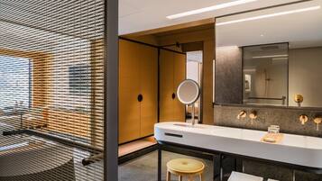 A modern bathroom with a large mirror, a bathtub, and a stool.