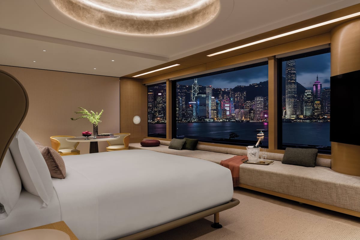 Une chambre d’hôtel moderne dotée d’un grand lit, d’un coin salon et offrant une vue sur la ville.
