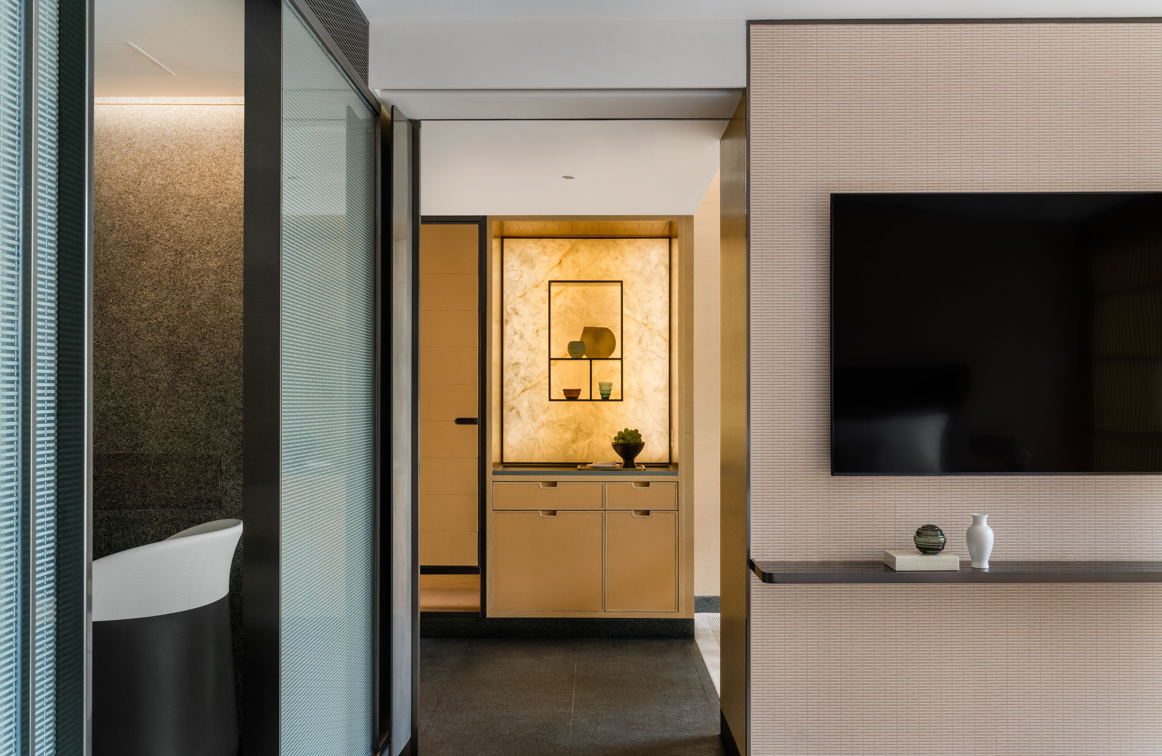 A modern bathroom with a glass partition, a white sink, and a marble backsplash.