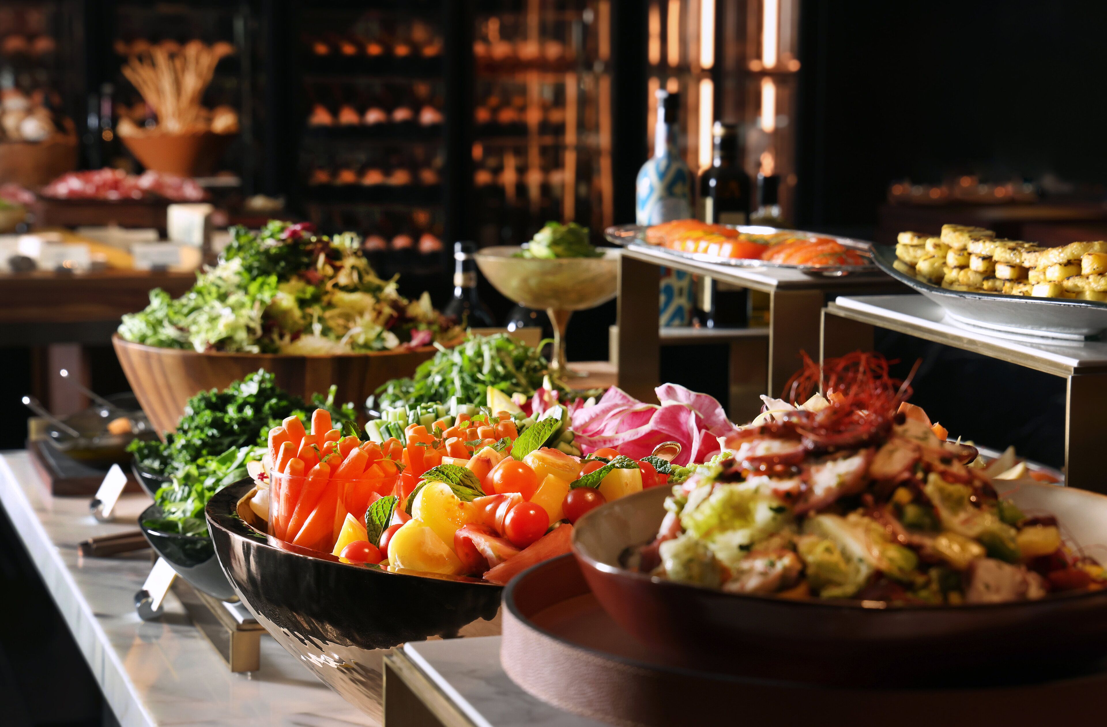 A buffet with various dishes including salads, vegetables, and meats.