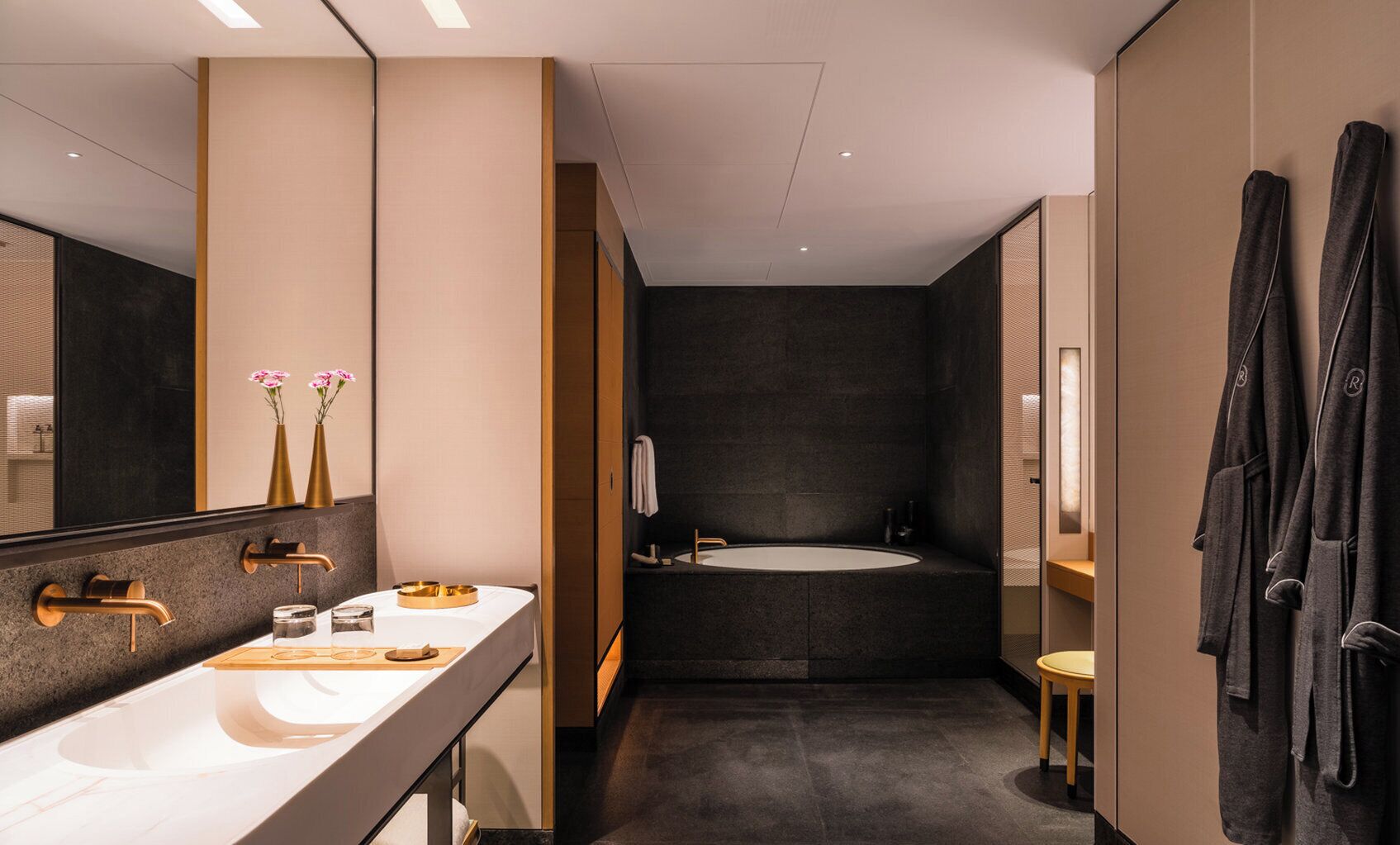 A modern bathroom with a double sink, a bathtub, and a large mirror.