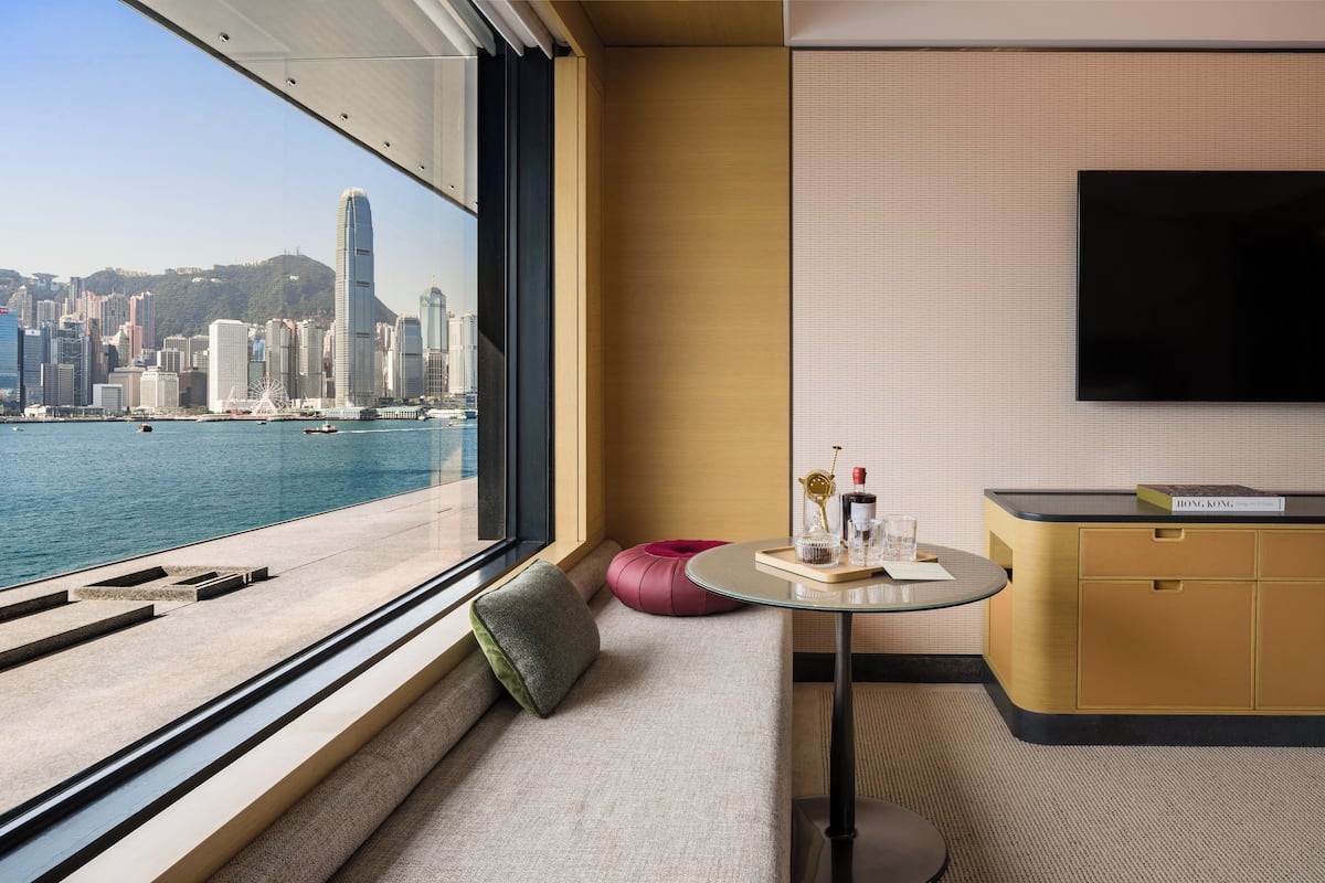 Une chambre d’hôtel moderne dotée d’une grande fenêtre donnant sur un paysage urbain et le front de mer.