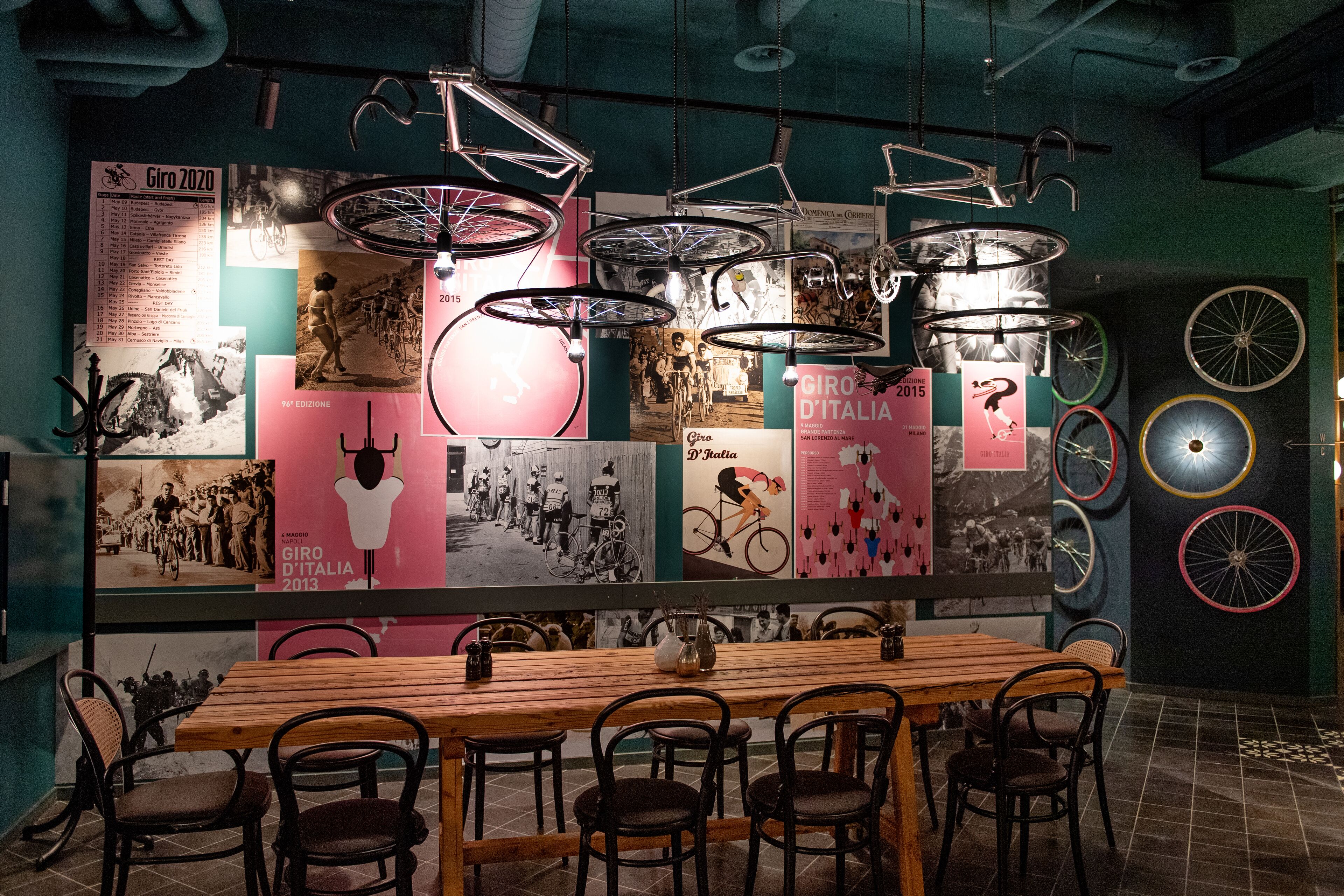 Un restaurante con una larga mesa de madera y sillas, rodeado de paredes decoradas con bicicletas antiguas y carteles.
