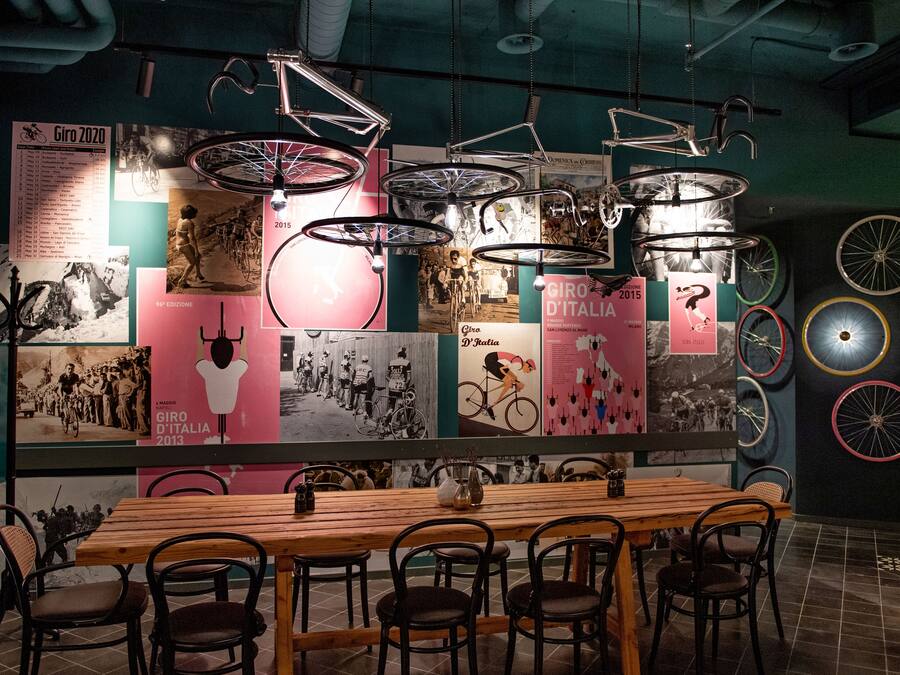 A restaurant with a long wooden table and chairs, surrounded by walls decorated with vintage bicycles and posters.
