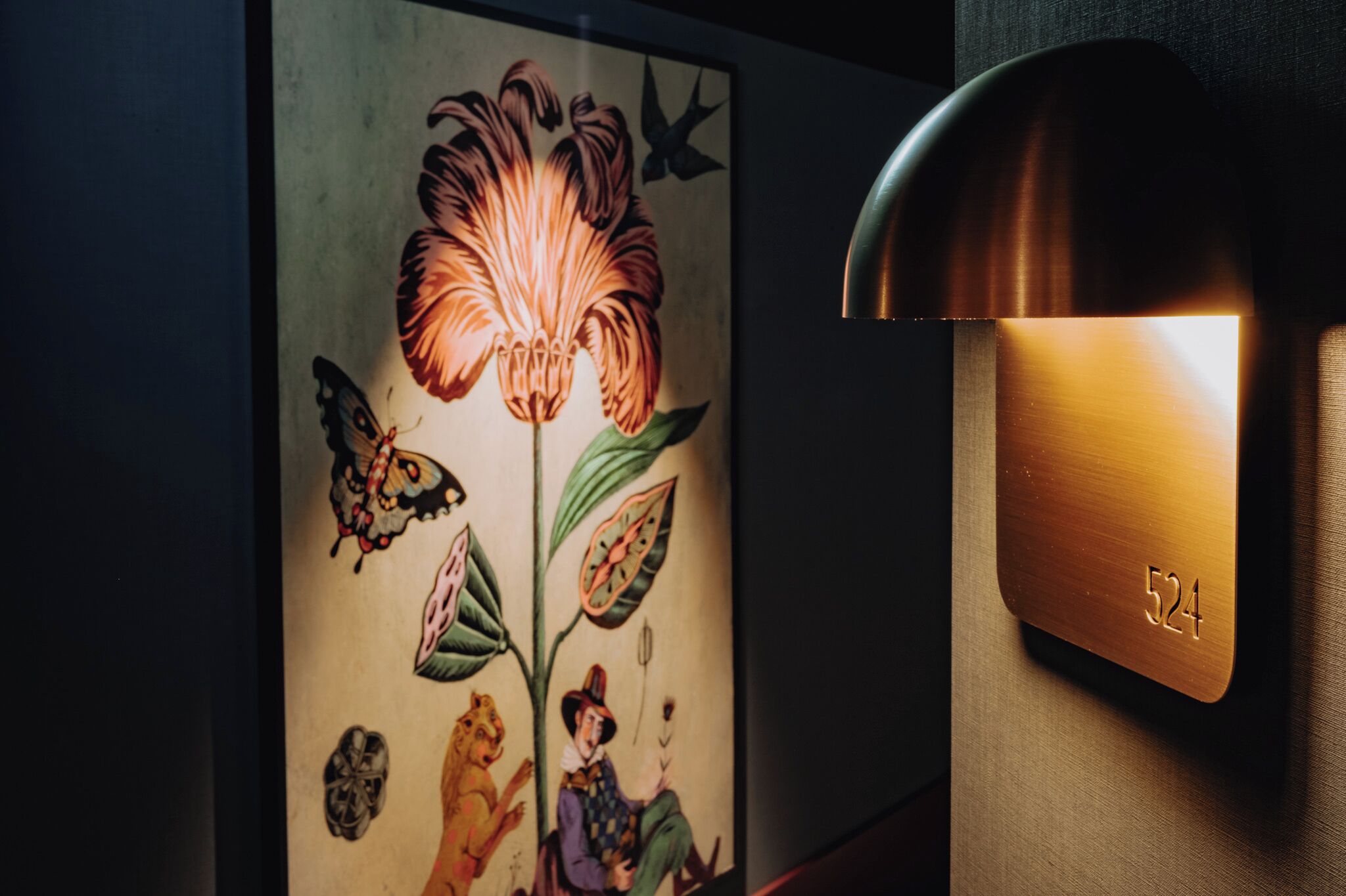 A wall-mounted light fixture with a number "524" and a colorful mural with butterflies and a tiger.