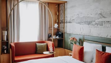 A hotel room with a bed, a sofa, a desk, and a large window with curtains.