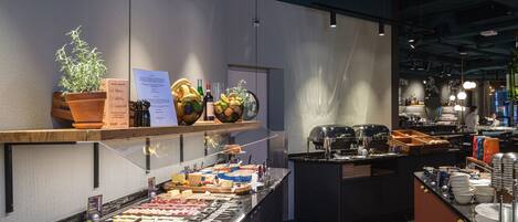 Un área de bufé con diversas opciones de comida, una barra de ensaladas y una zona de bar con un barman.