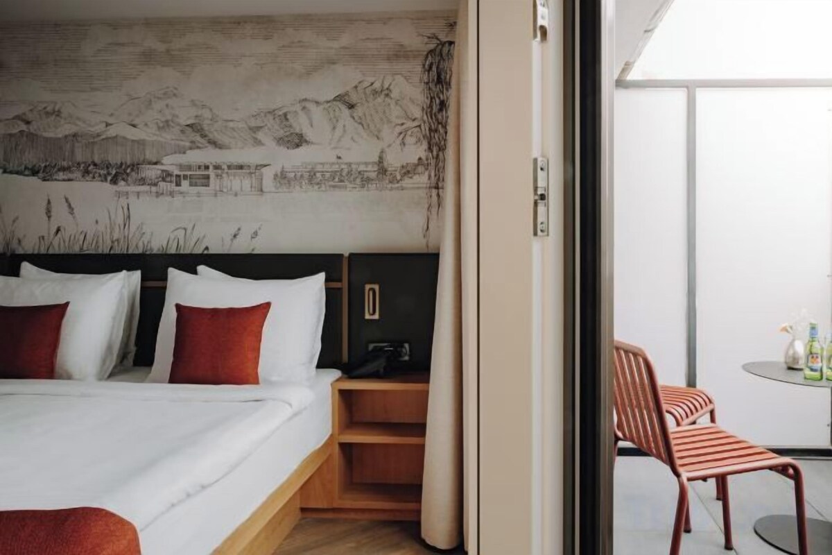 A hotel room with a bed, a desk, and a view of the outside.