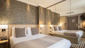 A hotel room with a large bed, a bedside table with a lamp, a mirror, and a wall with a leaf pattern. - Prince Albert Lyon Bercy (Paris)