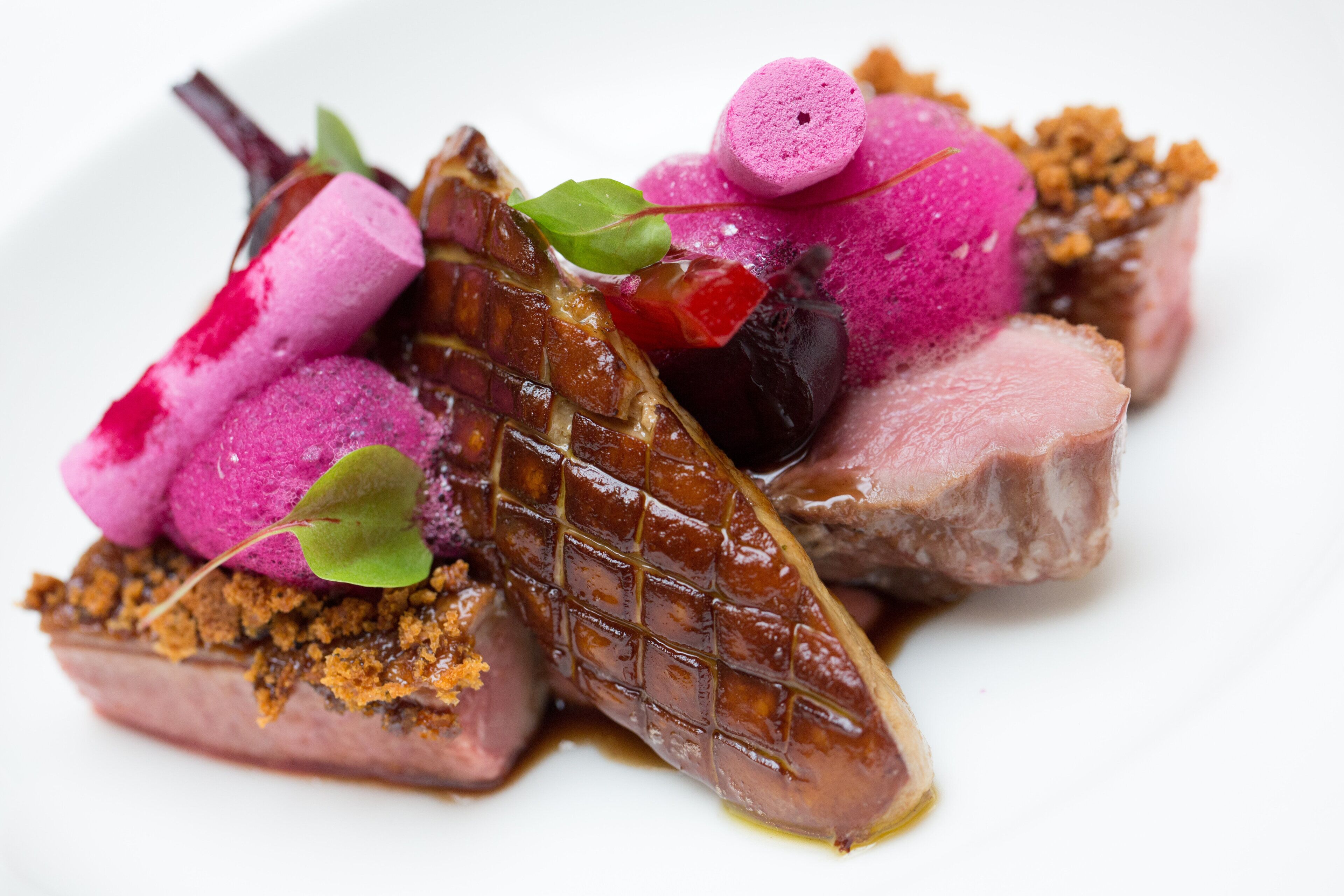 A dish with various food items including meat, vegetables, and garnishes.