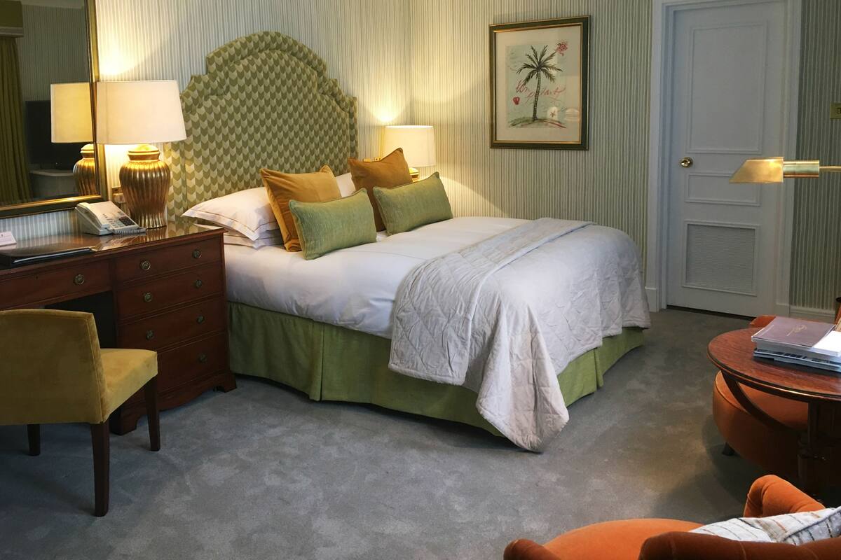 A neatly arranged bedroom with a bed, bedside tables, a dresser, and a chair.