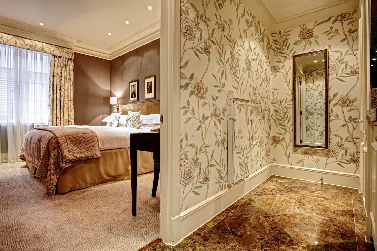 A bedroom with a bed, a nightstand, a lamp, and a large mirror.