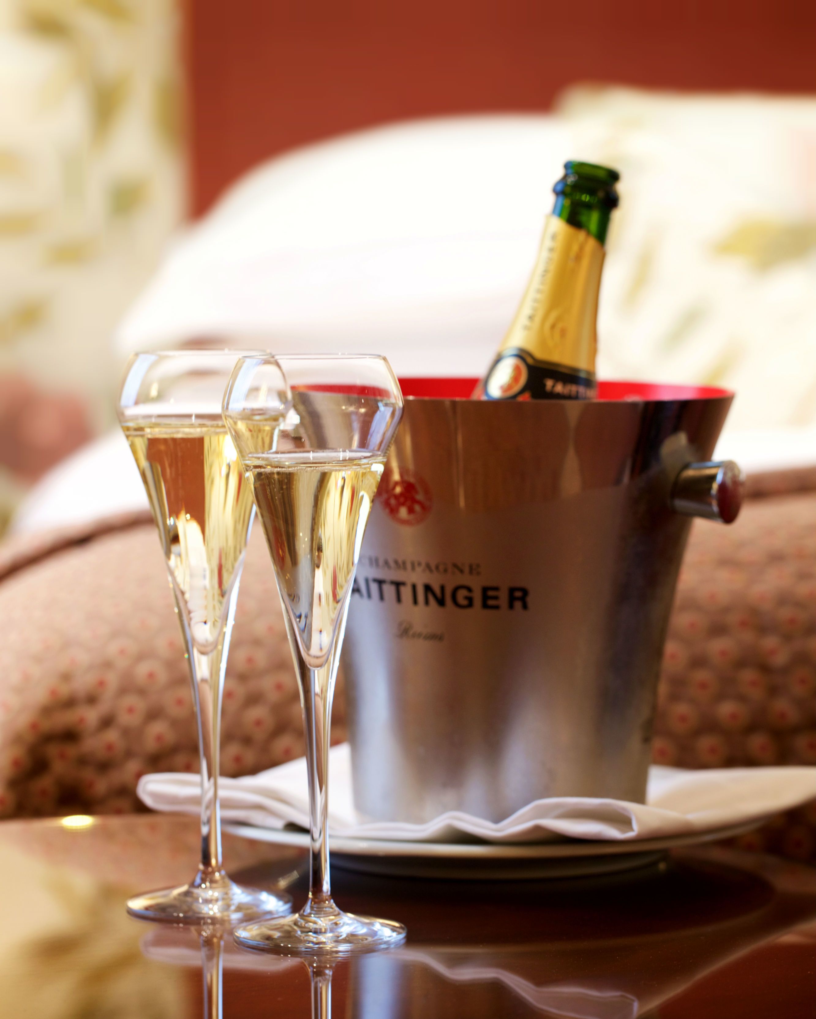 Deux flûtes à champagne sont posées sur une table, à côté d’une bouteille de champagne dans un seau à glace.