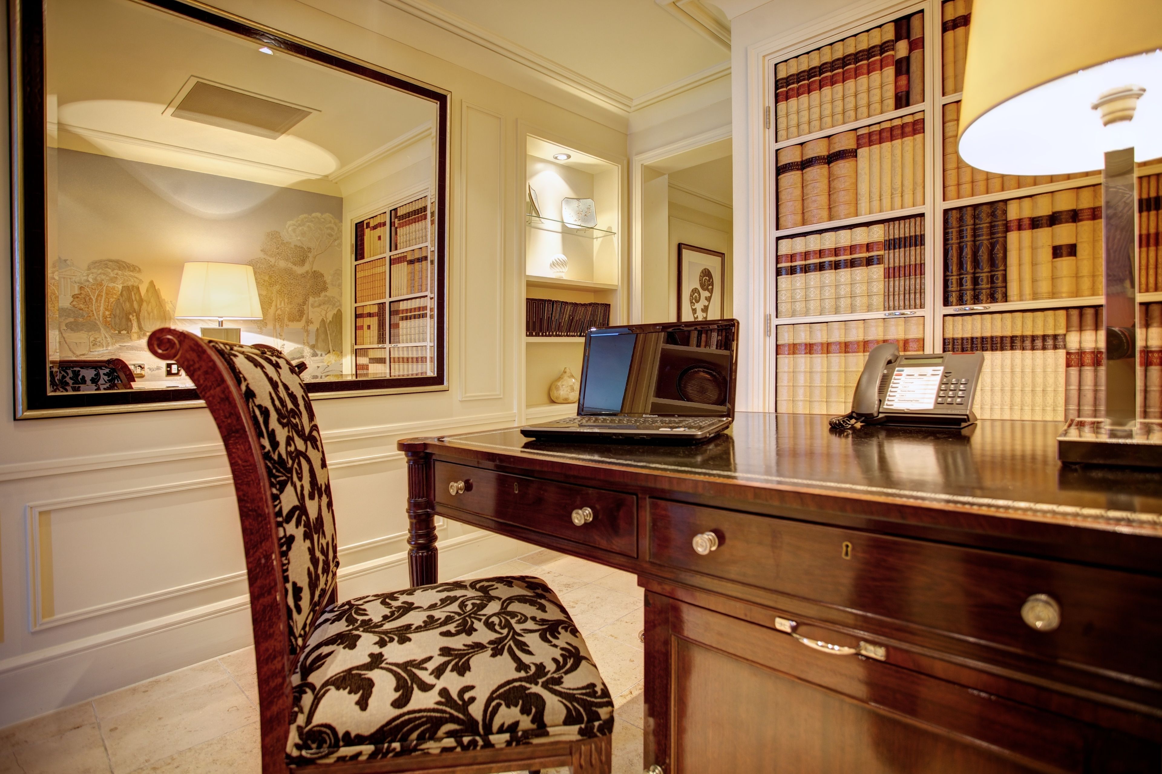 A study with a desk, chair, laptop, telephone, and bookshelves.