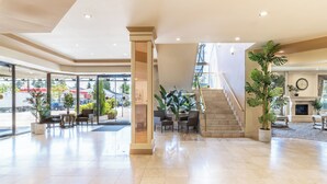 Un vestíbulo amplio con escaleras, zona de estar y grandes ventanales.