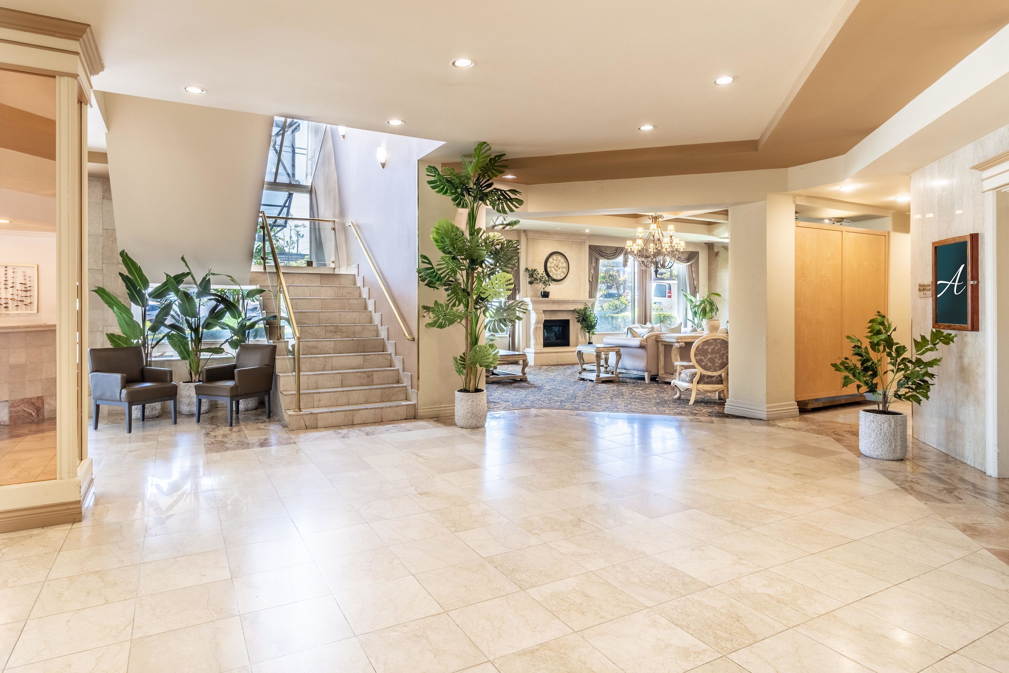 Eine geräumige Lobby mit Treppe, Sitzgelegenheiten und Kamin.
