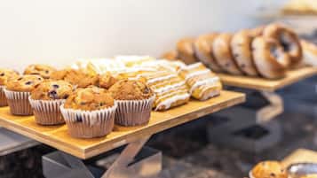 A variety of baked goods displayed on a wooden table, including muffins and bagels.