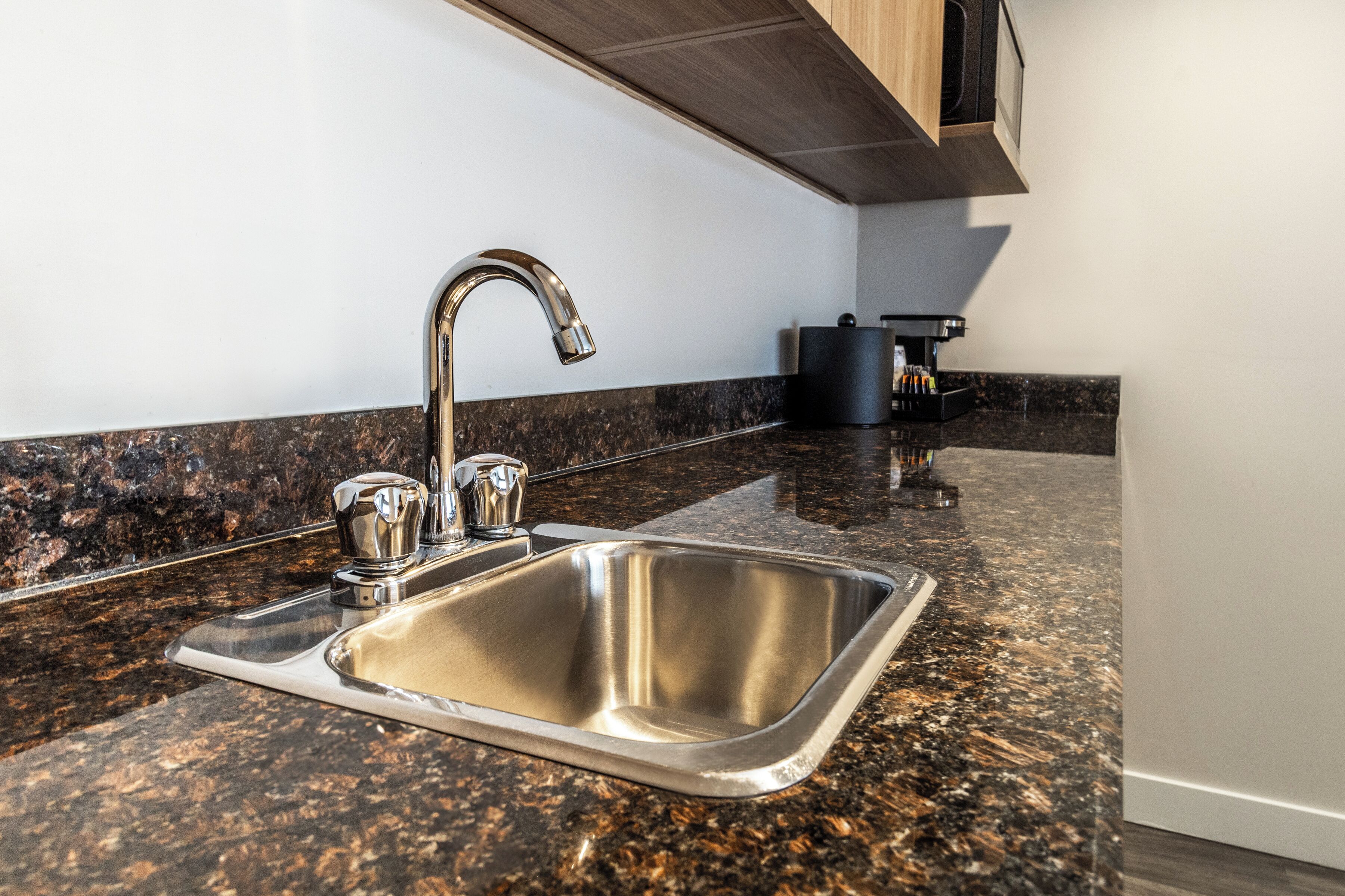 Cuina amb rentamicrodats d'acer inoxidable, taulell de granit i armaris de fusta.