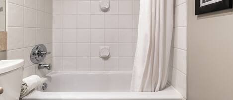 Un baño con bañera blanca, inodoro y lavamanos.