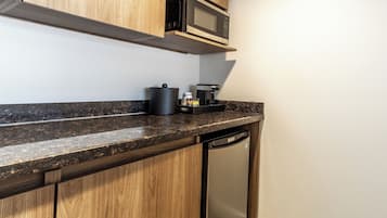 Una cocina con armarios de madera, microondas, cafetera y lavavajillas.