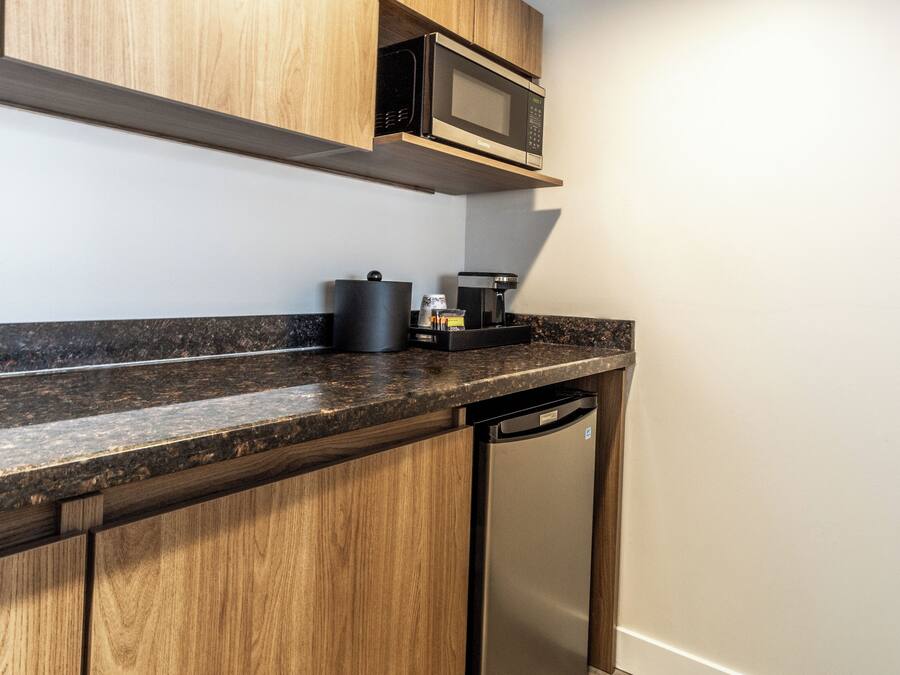 Una cocina con armarios de madera, microondas, cafetera y lavavajillas.