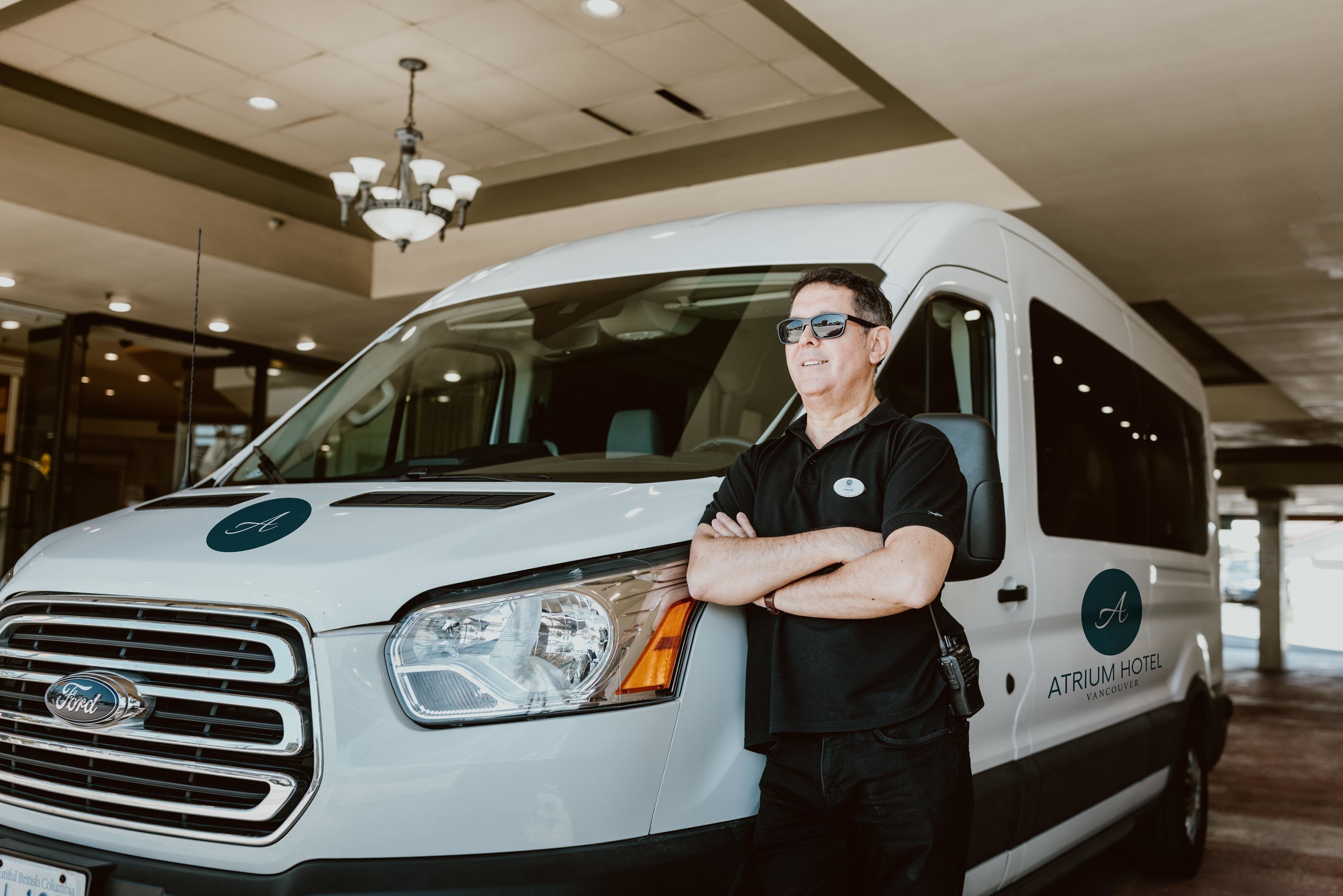 A white van with 'Atrium Hotel Vancouver' branding parked indoors.