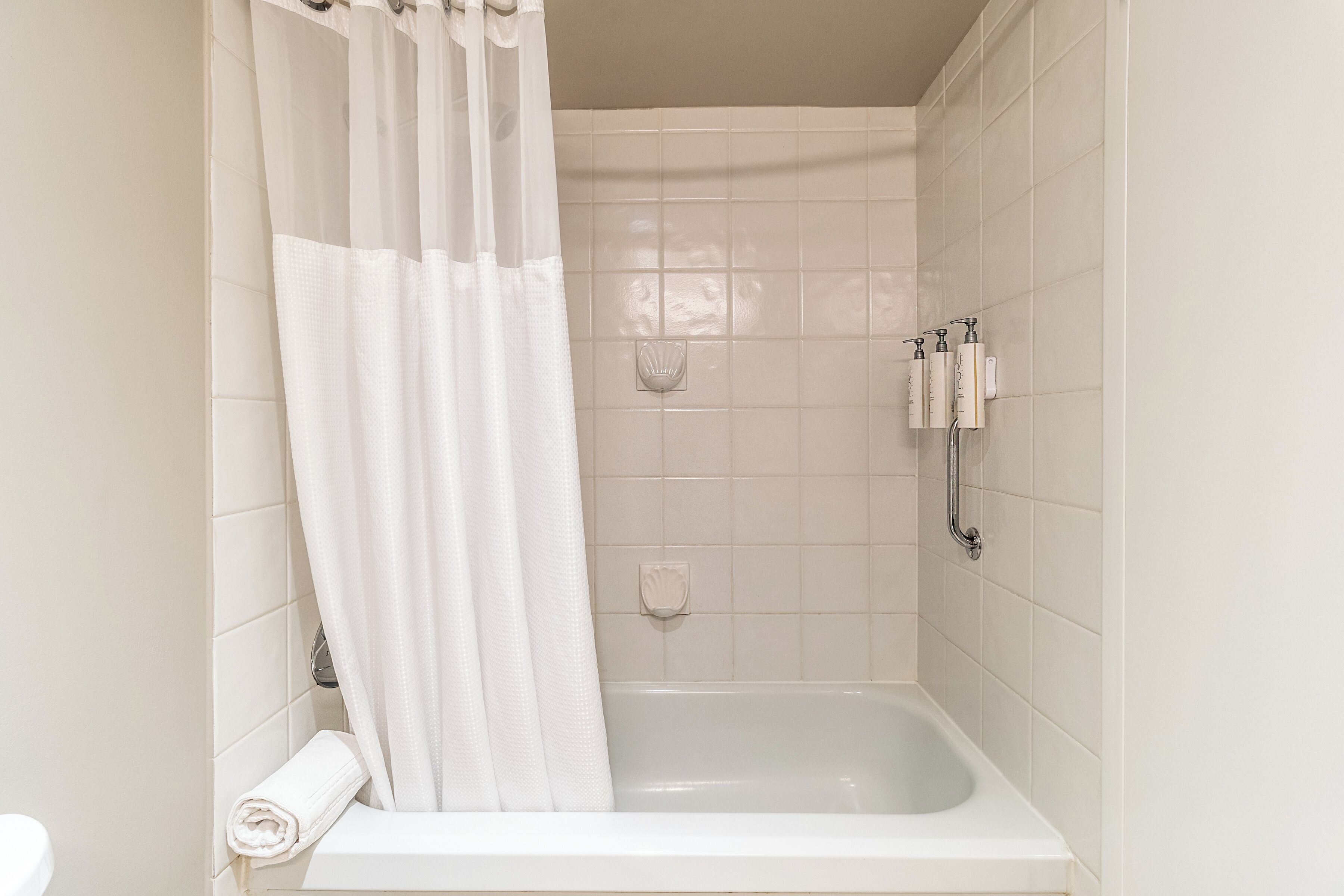 A bathroom with a bathtub, a shower curtain, and a towel rack.
