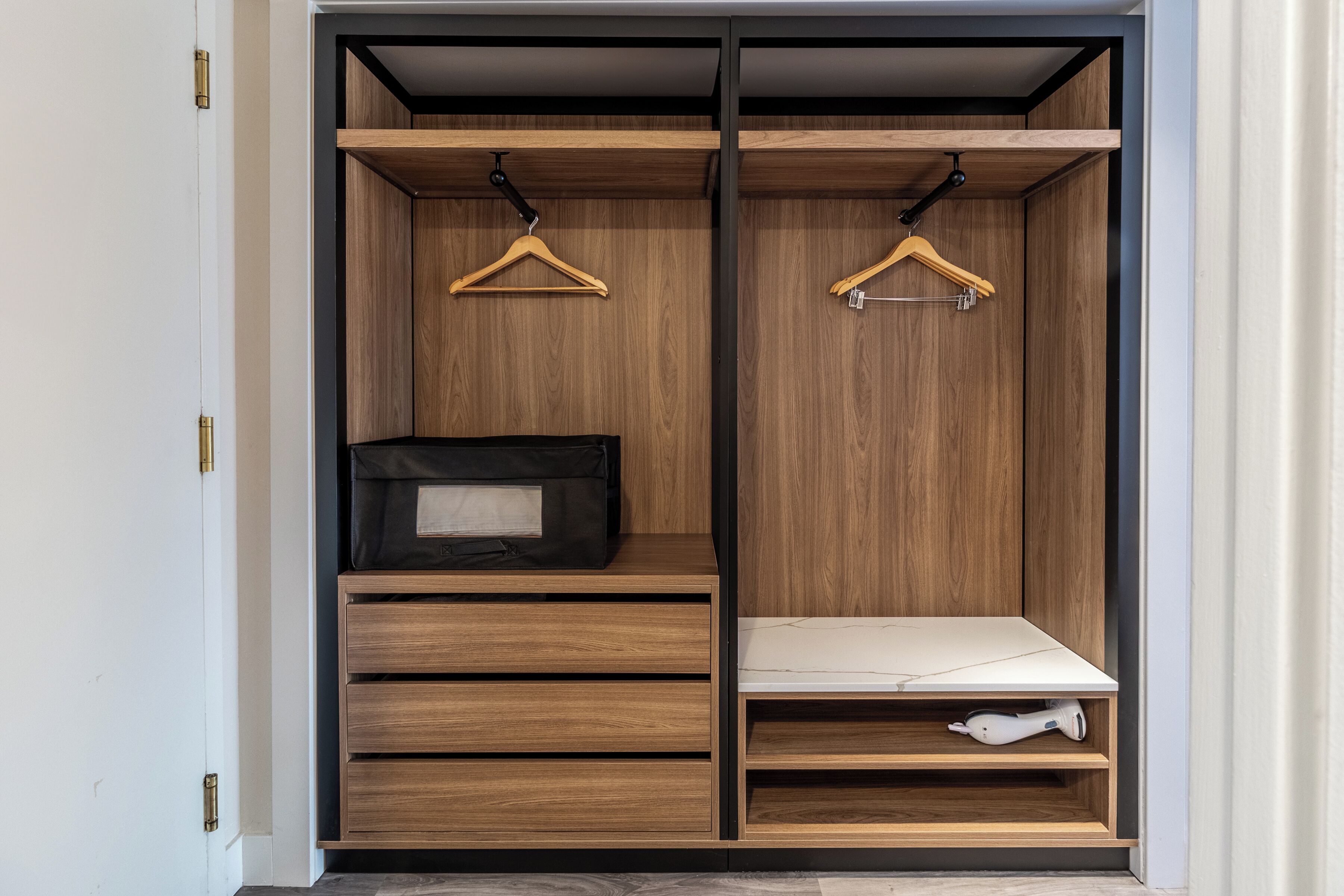 A walk-in closet with wooden shelving, a black bag on the left, and a white item on the right.