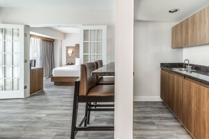 Una habitación de hotel moderna con comedor, kitchenette y una cama grande.