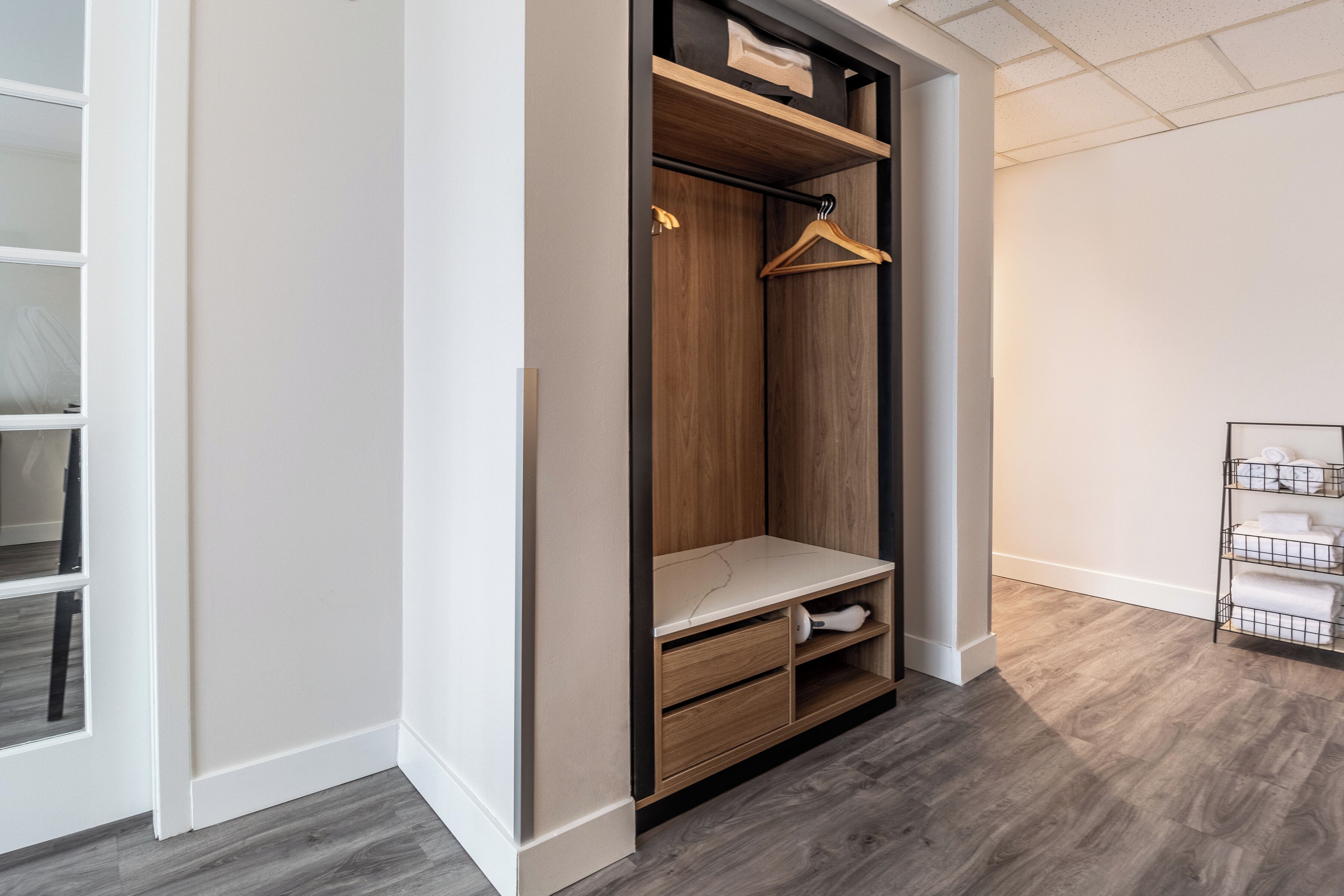 A walk-in closet with wooden shelving, a hanging rod, and a bench.