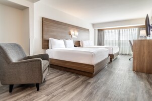 Habitación de hotel con una cama grande, una silla, un escritorio y vistas al exterior.