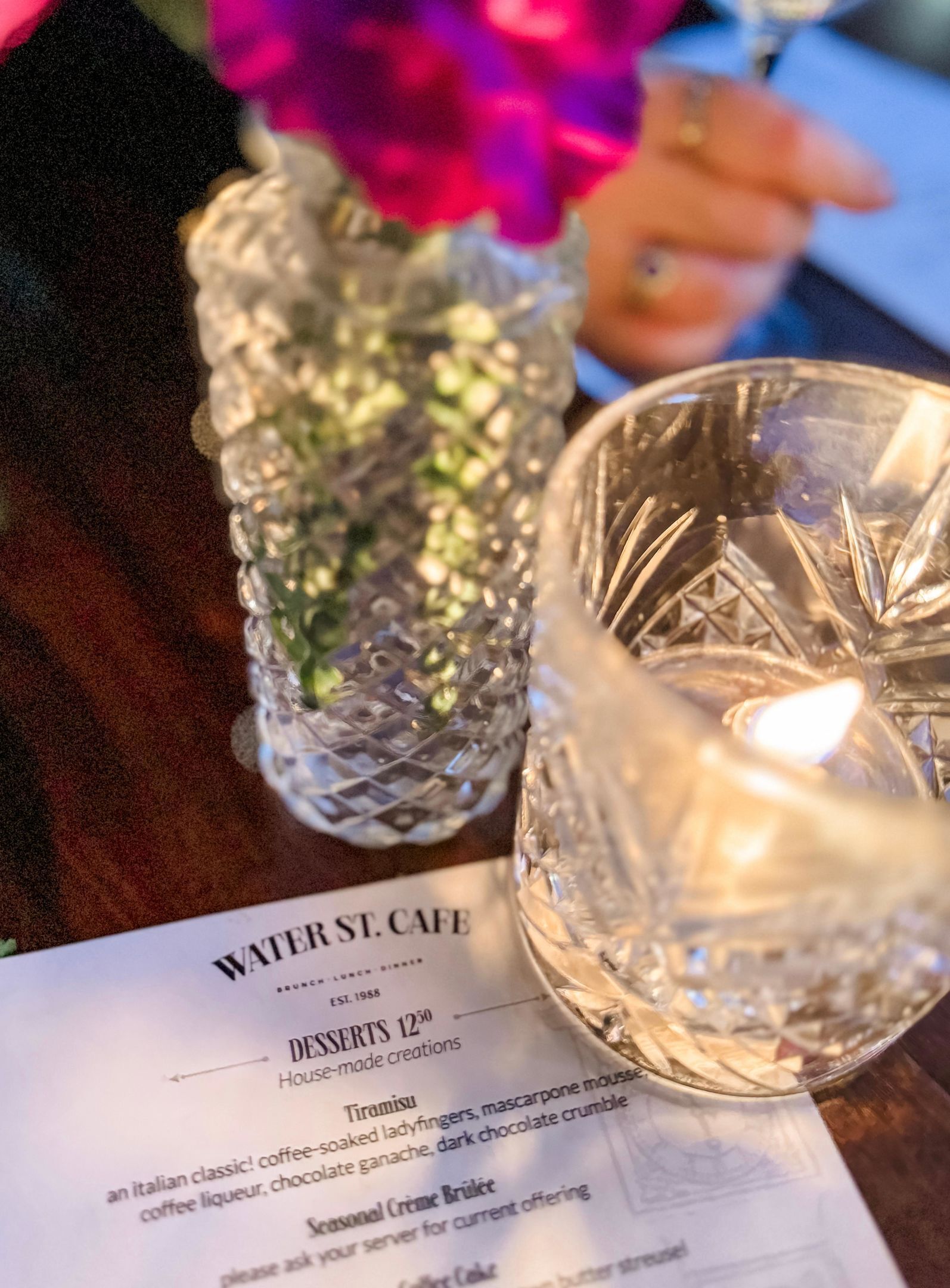A menu from Water St. Cafe with a section titled 'Desserts 1250' and a candle in a glass holder.