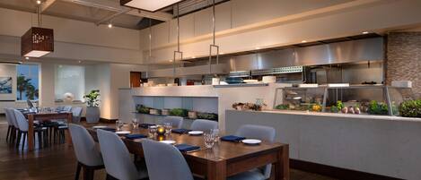 A modern restaurant with a wooden dining area, a bar, and a kitchen.